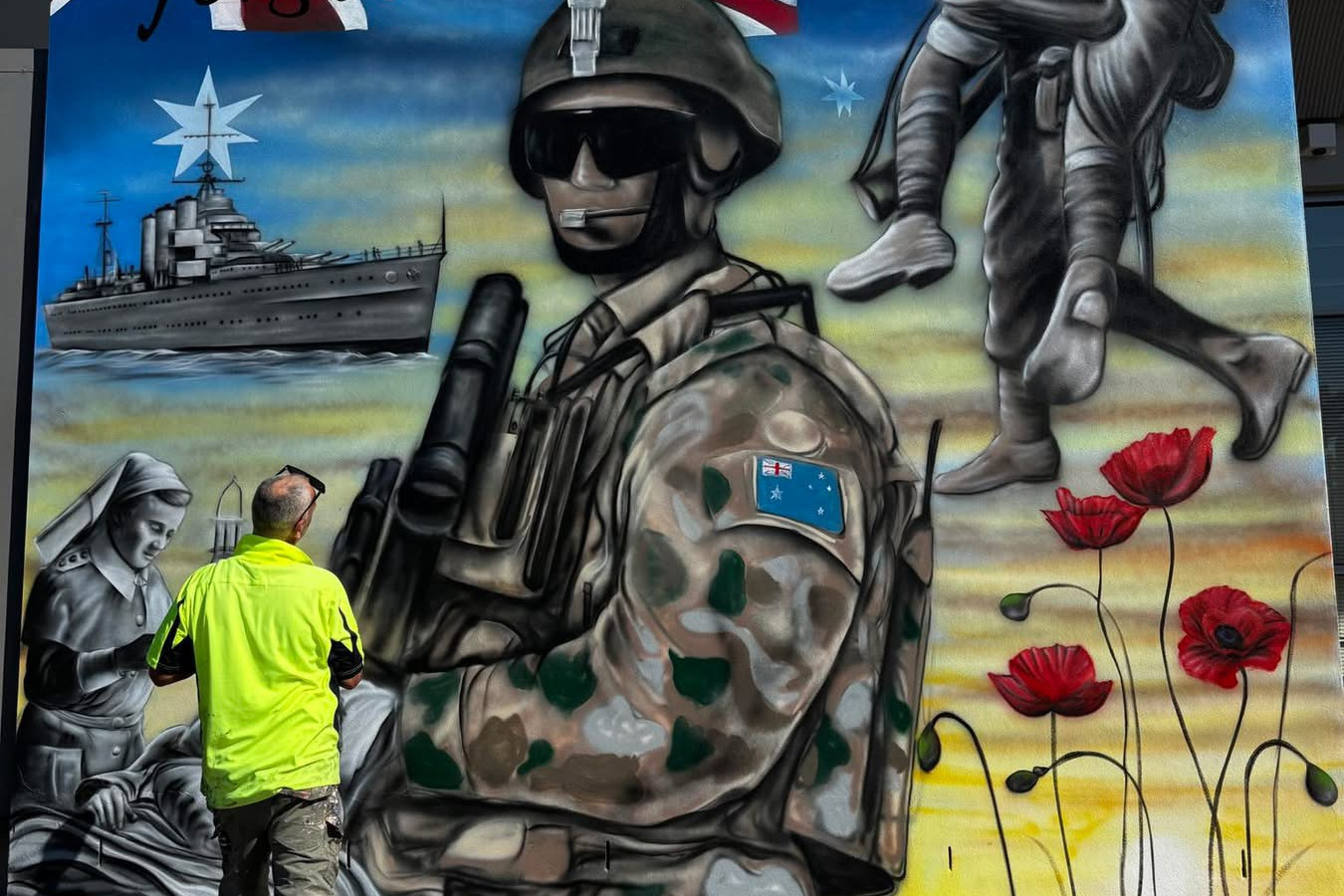Simon White applying the finishing touches to his ANZAC mural at West Wyalong's S&C Club